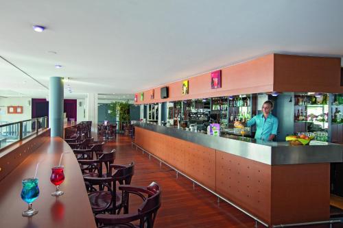 a man standing behind a bar in a restaurant at Hotel Belambra Le Normont in Dourdan