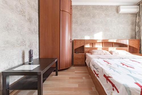 a bedroom with a bed and a desk in it at Уютная квартира in Astana
