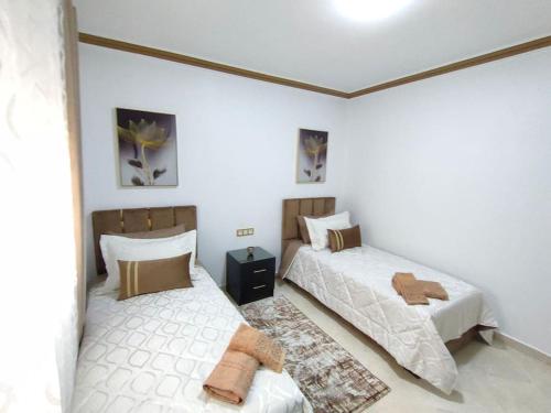 - 2 lits dans une chambre aux murs blancs dans l'établissement Merveilleux Appartement pour un séjour de Top., à Tanger