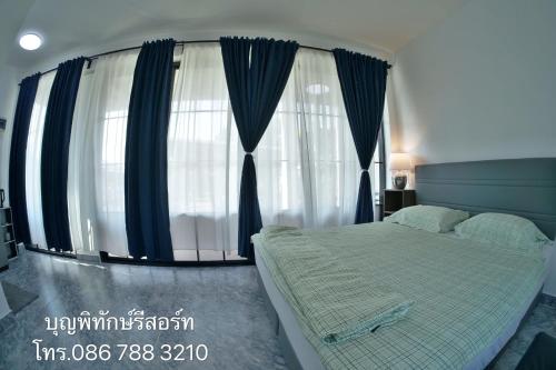 a bedroom with a bed and a large window at บุญพิทักษ์รีสอร์ท in Thung Saliam