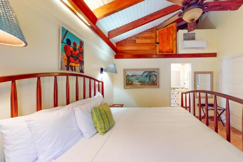 um quarto com uma cama branca e um tecto de madeira em Condo #27 @ Beachside Villas em Dangriga