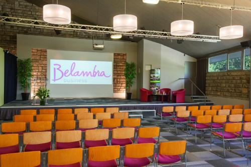 a lecture hall with orange chairs and a large screen at Hotel Belambra Le Normont in Dourdan