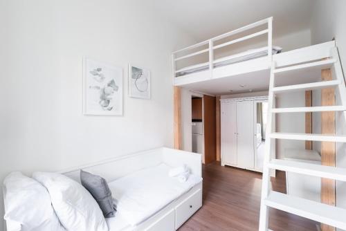 een witte slaapkamer met een stapelbed en een ladder bij Budget Reznicka apartment in Praag