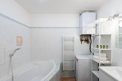 a white bathroom with a tub and a sink at Budget Reznicka apartment in Prague