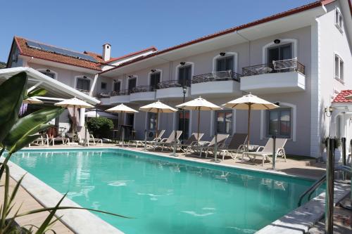 a swimming pool in front of a building with chairs and umbrellas at Caretta - Caretta Hotel in Ligia