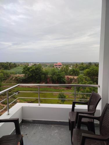 a balcony with two chairs and a view of a field at SKS Residency in Mahabalipuram