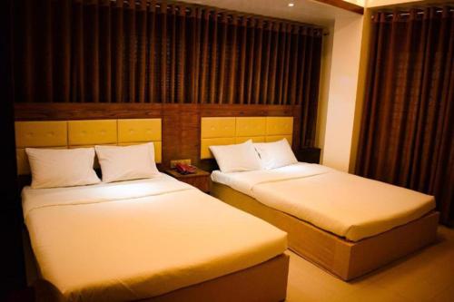 two beds in a hotel room with two bedsskirts at The Alina Hotel & Suites in Chittagong