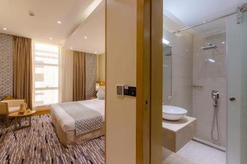 a bedroom with a bed and a bathroom with a shower at Qasr Al Sahab Hotel Makkah in Makkah