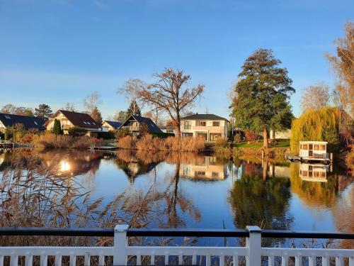 - Vistas a un lago con casas y una valla en Ferienhaus mit Wasserterrasse - mit Sauna und Kamin - inklusive Nebenkosten, en Wendisch Rietz