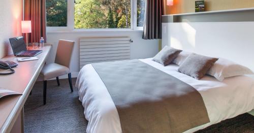 a bedroom with a bed and a desk and a laptop at Hotel Belambra Le Normont in Dourdan