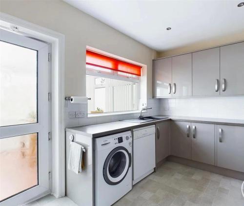 a kitchen with a washing machine and a window at Mordern home in Kippax