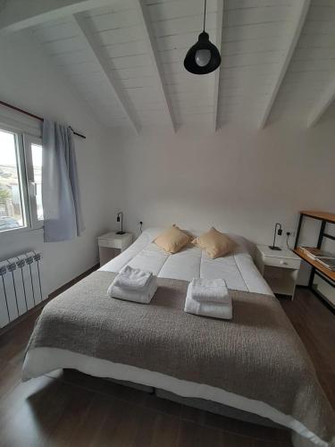 a white bedroom with a large bed with two pillows at VERA Apart in El Chalten