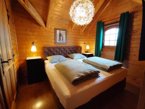 ein Schlafzimmer mit einem großen Bett in einem Holzzimmer in der Unterkunft Chalet Familienzeit in Lathum