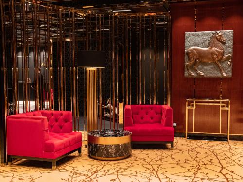 a lobby with two red chairs and a horse on the wall at Mandarin Club House in Batumi