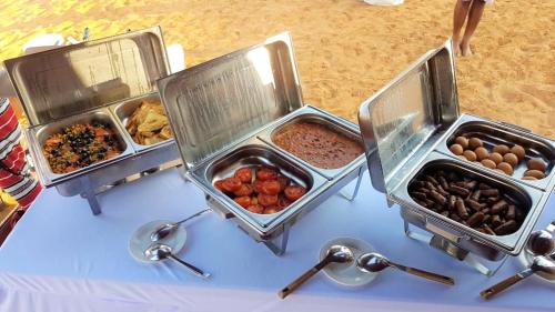 drei Tabletten mit verschiedenen Arten von Lebensmitteln auf einem Tisch in der Unterkunft Desert Moments Glamping - full privacy in Muntarib
