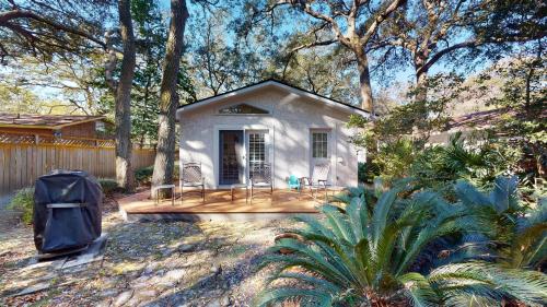 a small white house with a porch in a yard at AZALEA COTTAGE DUPLEX Duplex in Jekyll Island