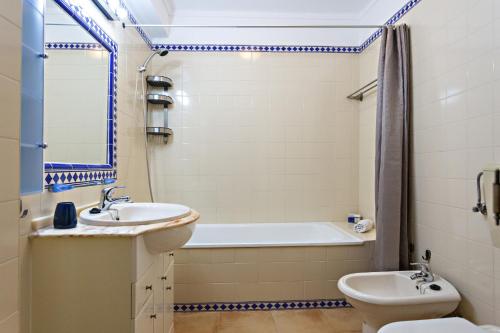 a bathroom with a sink and a tub and a toilet at Cabanas Vintage Apartment in Tavira