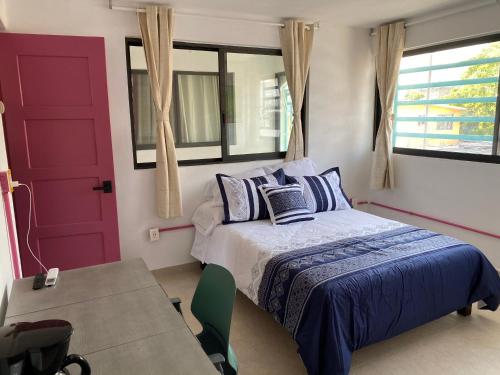 een slaapkamer met een bed en een rode deur bij Hotel Casa Mandarine , Amazing Private Rooms w Balcony, Rooftop, Hammocks, AC, SmarTV, 100mbs! in Zihuatanejo
