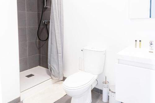 een witte badkamer met een toilet en een douche bij Le Combarel in Rodez