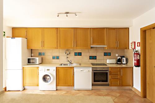 a kitchen with wooden cabinets and a white refrigerator at Camélia Apartment in Santa Luzia