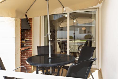 a table and chairs on a balcony with an umbrella at Camélia Apartment in Santa Luzia