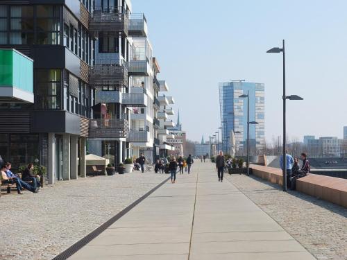 people walking down a sidewalk in a city with buildings at Süsses Motorboot - Bremen Überseestadt in Bremen
