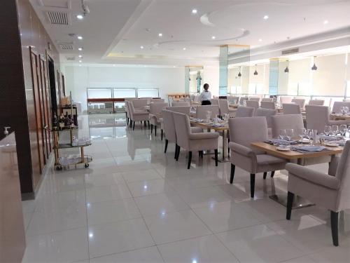罗安达Hotel Express的一间有桌椅的餐厅，背景中有一个人物