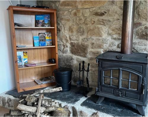 a black stove in a room with a stone wall at L'Annexe in Maël-Pestivien