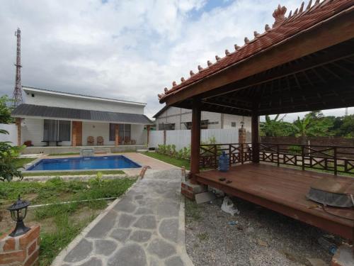 a house with a wooden deck and a swimming pool at Villa Sawah Prambanan in Randugunting