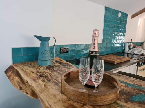 a bottle of wine and two wine glasses on a counter at The Old Pottery 2 Person Dog Friendly Cottage in Delabole