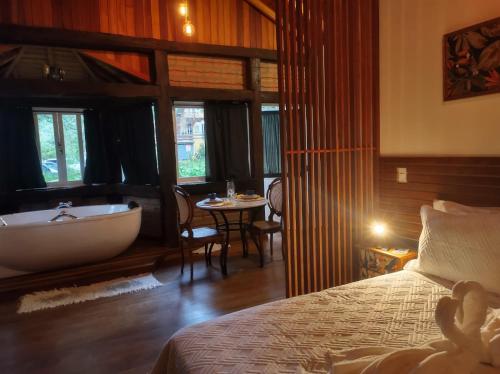 1 dormitorio con bañera, cama y mesa en Casa De Férias e Hospedagem Ana Lua en Visconde De Maua
