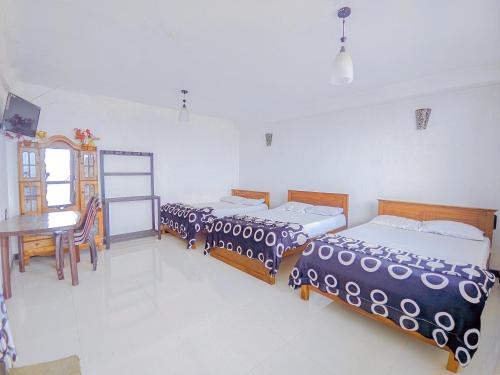 two beds in a room with a table and a tableablish at White Home in Haputale
