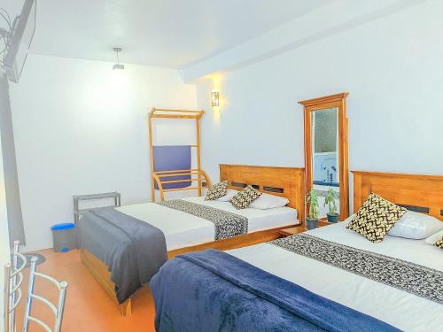 a hotel room with two beds and a mirror at White Home in Haputale