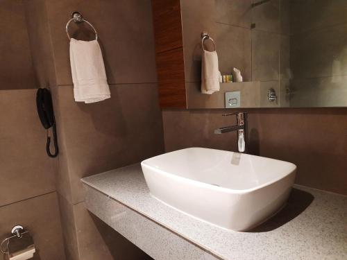 a bathroom with a white sink on a counter at Hotel Kottayam Grand in Kottayam