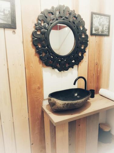 une salle de bain avec un lavabo noir et un miroir dans l'établissement L'Échappée belle à l'Étang d'Anty -appartement, à Saint-Nabord