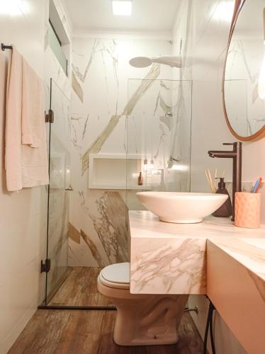 a bathroom with a sink and a toilet and a mirror at Flat Canto dos Pássaros in Itacaré