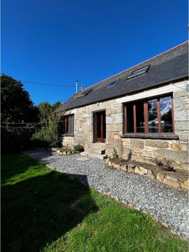 a stone house with a gravel path in front of it at Maison de Maison in Maël-Pestivien