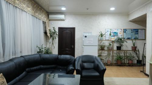 a living room with a black leather couch and a refrigerator at Apple Hostel Bishkek in Bishkek