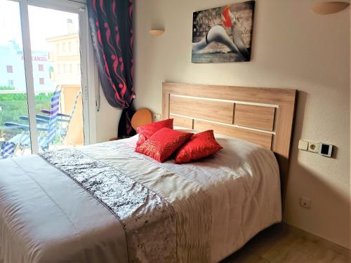 um quarto com uma cama com almofadas vermelhas e uma janela em Global Immo 3064 Thalassa Playa em Roses