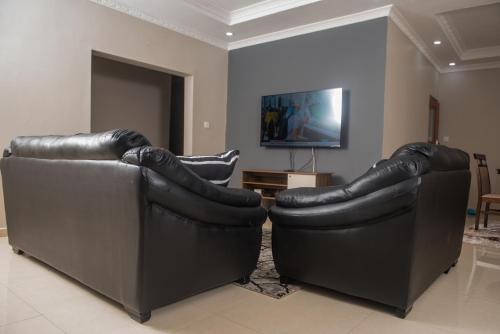 dos sofás de cuero negro sentados en una sala de estar en JC Apartments, en Ndola