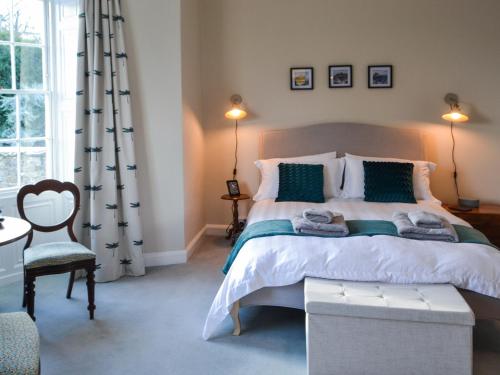 a bedroom with a bed and a chair and a window at Number 1 in Alnwick