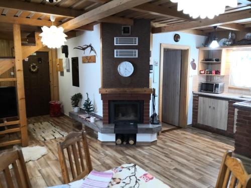 a living room with a fireplace and a clock on the wall at Chata pod pilskom in Sihelné