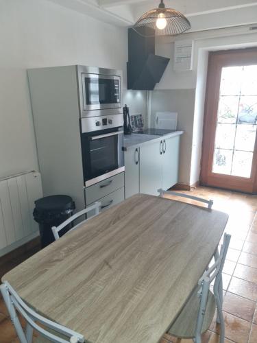 une cuisine avec une table en bois et des chaises. dans l'établissement Jolie petite maison dans village fortifié, à Brigueuil