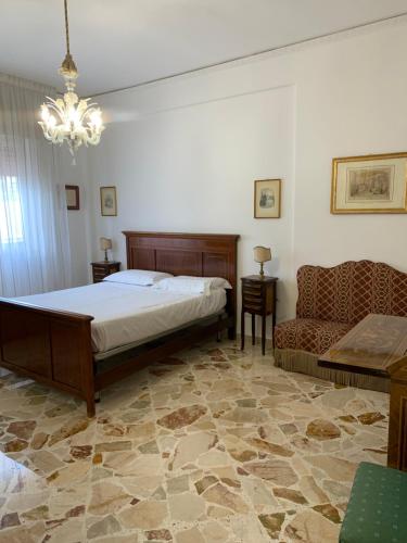 1 dormitorio con cama, sofá y lámpara de araña en La Baronessa, en Carini