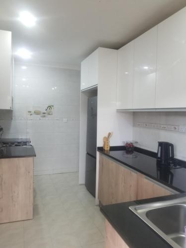 eine Küche mit weißen Schränken und einer schwarzen Arbeitsplatte in der Unterkunft JC Apartments in Ndola