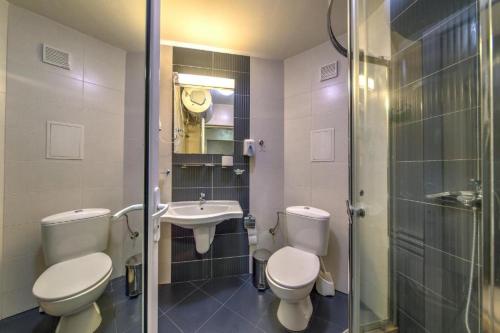 y baño con 2 aseos, lavamanos y ducha. en Форест Нук - апартамент, en Pamporovo