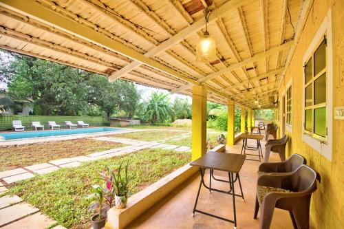 a patio with a wooden pergola with chairs and a table at Luxury 6 BHK Villa with Private Swimming Pool Near Calangute & Baga in Old Goa