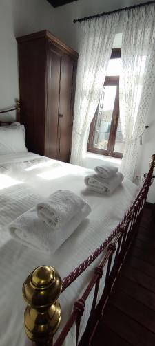a bedroom with a bed with white sheets and a window at Αρχοντικό Ταξίμι (Μουντζουρίδη) in Argalasti