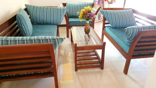 a room with three chairs and a table with a vase of flowers at Chenu Villa Hikka in Hikkaduwa