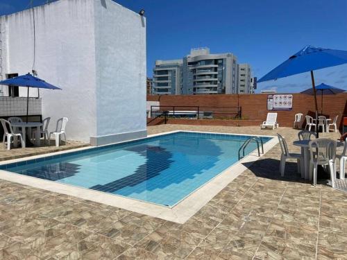 a swimming pool with chairs and umbrellas on a building at APARTAMENTO EM LOCAL PRIVILEGIADO in Maceió